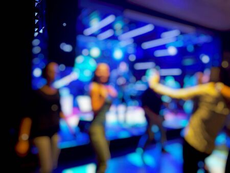 Scene with light musicians on stage in the rock cafe people dancing around the stage blur effect