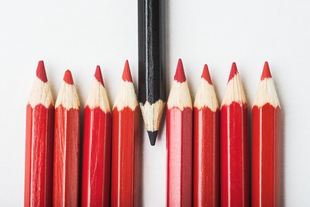 Inverted black pencil among of red pencils individuality concept Stock Photo