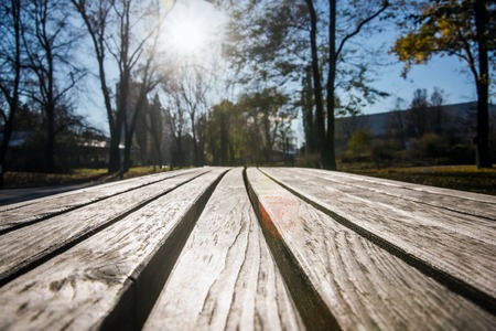Detalle de un banco de madera vacío en un parque público de la ciudad con sol. Perspectiva diferente