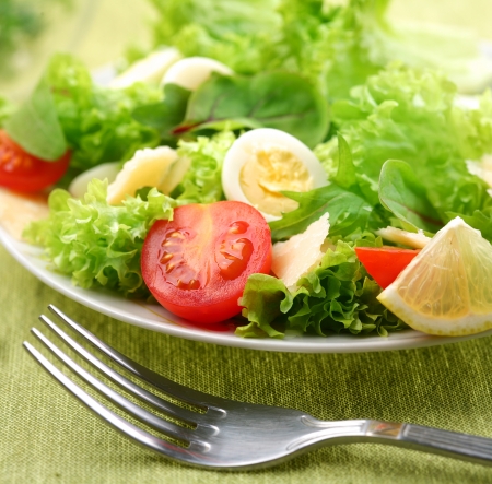 Fresh salad with tomato and quail eggs on a green tablecloth