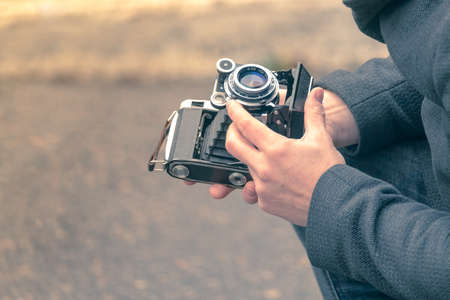 Mężczyzna trzyma zabytkowy, ale działający aparat i ustawia go do fotografowania na ulicy Zdjęcie Seryjne