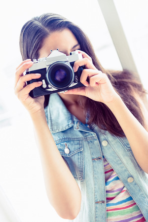 Smiling young woman taking a photo in a bright room