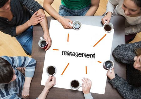 The word management on page with people sitting around table drinking coffee Stock Photo