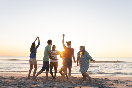Diverse group of friends enjoy a beach sunset the group creates a lively outdoor atmosphere