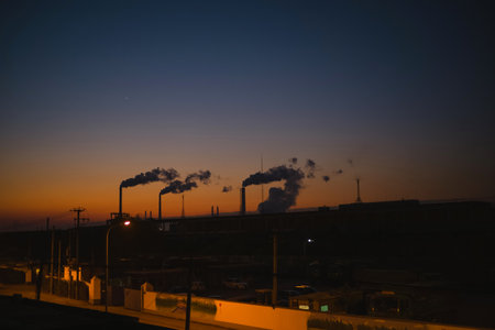 Industrial landscape with smokestack and chimneys at sunset