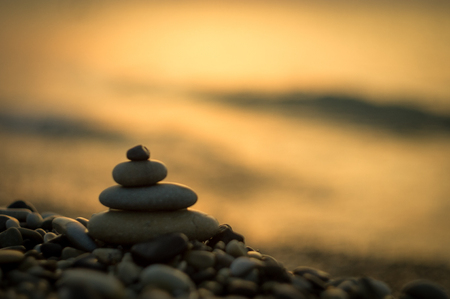 Folded pyramid zen pebble stones on the sea beach at sunset