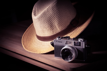 Old camera with hat on wooden table still lift and vintage effect