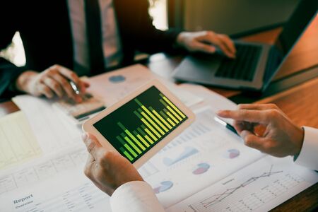 Two businessmen are working analyzing the company annual budget and using digital tablet to find information data result