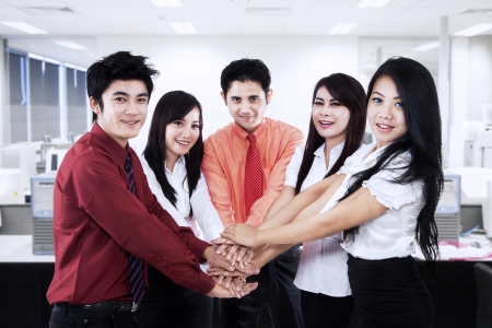 Asian business team showing unity by joining their hands together