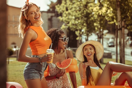 Un tiempo de picnic. Activa, feliz, encantadora, radiante, encantadora, delgada, radiante, encantadora, tres amigas disfrutando del tiempo libre durante un picnic al aire libre.