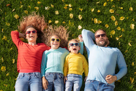 Retrato de familia feliz al aire libre. Padre, madre, hija e hijo divirtiéndose en el parque de otoño. Vista superior