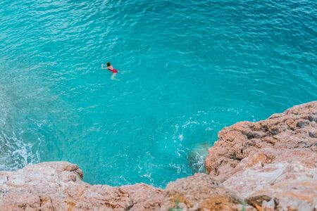 Imagen de una hermosa joven nadando copia espacio aislado sobre fondo de mar turquesa. Una niña lleva un traje de baño rojo en el mar Adriático. Foto de archivo