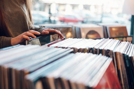 Manos de mujer seleccionando registros en una tienda. mujer joven hipster audiófilo en una tienda de discos. estilo antiguo y retro. concéntrese en las manos de la mujer navegando por un registro. copie el espacio. Foto de archivo