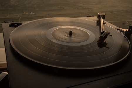 Tocadiscos de vinilo tocadiscos en el fondo de una puesta de sol sobre las montañas. Tecnología de sonido para que DJ mezcle y reproduzca música. Disco de vinilo negro. Tocadiscos de vinilo vintage. Aguja en un disco de vinilo