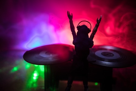 Dj club concept woman dj mixing and scratching in a night club girl silhouette on dj s deck strobe lights and fog on background creative artwork decoration with toy selective focus