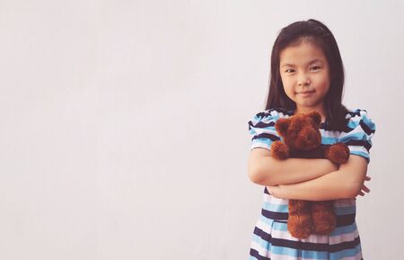 chica asiática abrazando a un oso de peluche