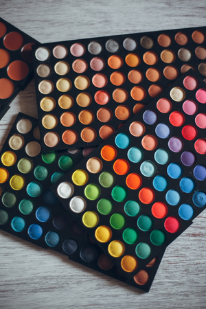 Multicolored eyeshadows on the white wooden table