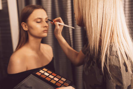 Make up artist doing professional make up of young woman