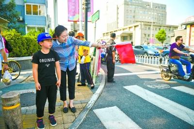 在台基厂路口，来自市直机关工委的志愿者正在对过街行人进行引导。 本报记者 邓伟摄