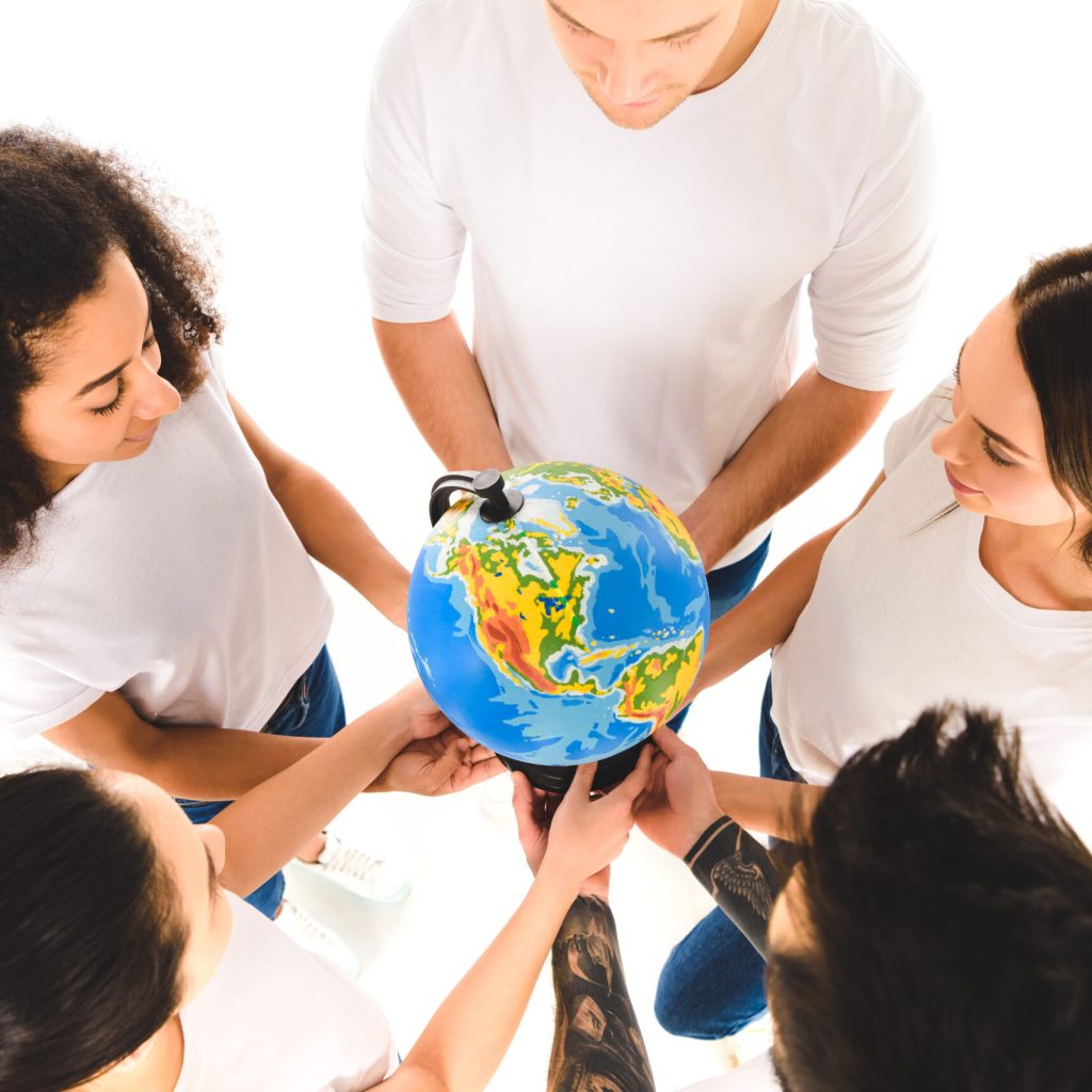 overhead view of multicultural group holding globe and standing in circle isolated on white