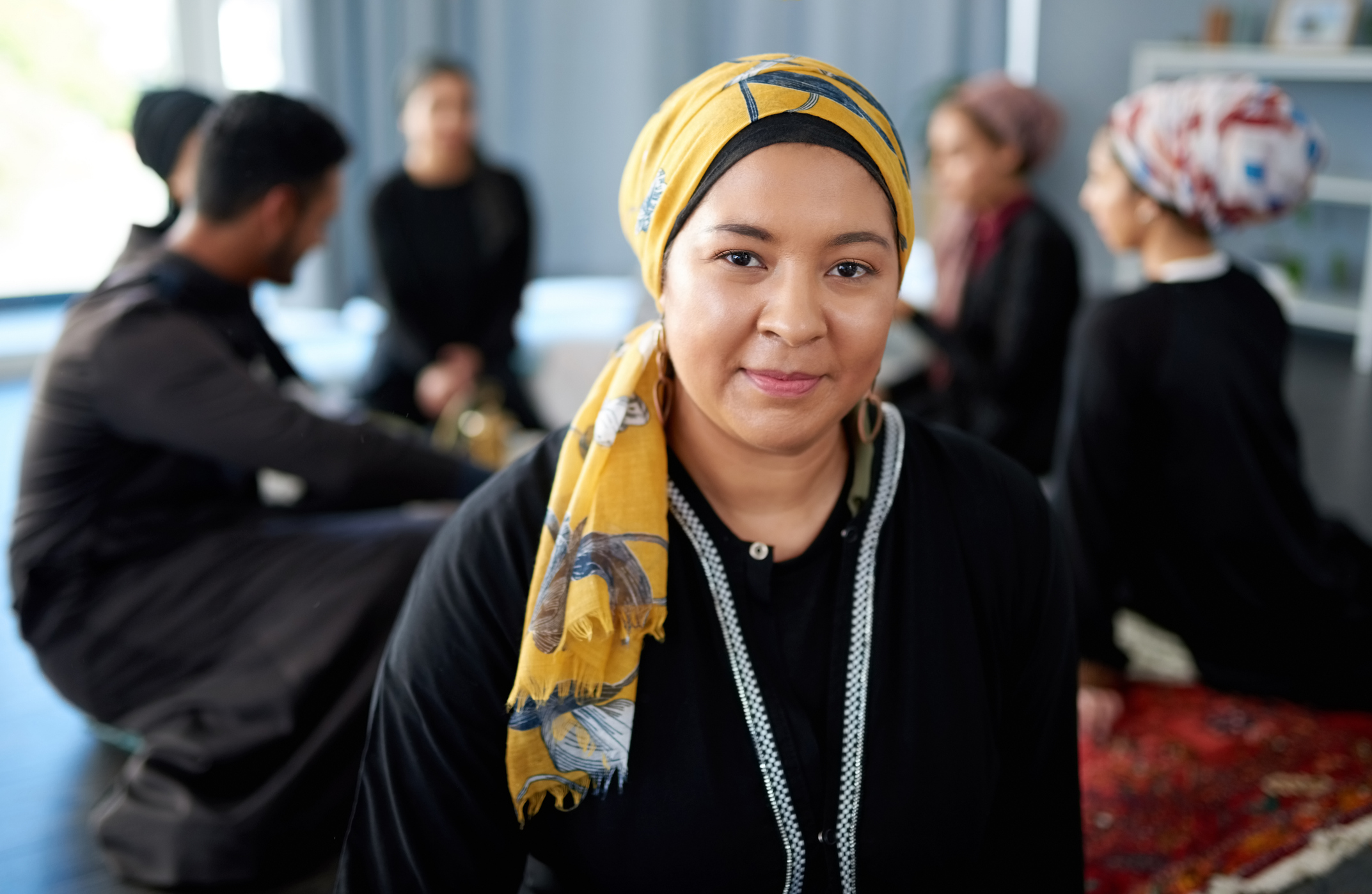 Portrait of a beautiful young muslim woman at a gathering with friends indoors