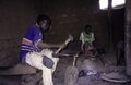 An iron smith in the blacksmith quarter is working indoors on a sickle with a hammer, 2001