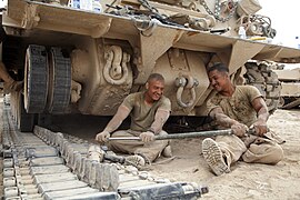 Deux hommes avec une barre à mine à côté d'une chenille étalée.