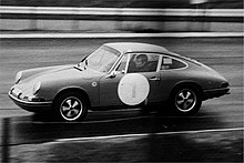 photo en noir et blanc d'une voiture aux formes arrondies allant vite avec un gros 1 sur la portière