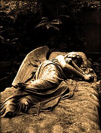 On the top of the grave lies a sleeping angel on a bed of clouds. 'In Ever Loving Memory of Mary, the darling wife of Arthur Nichols and fondly loved mother of their only son Harold who fell asleep 7 May 1909. Also of Dennis Arthur Charles son of Harold and Winifred who died 28 April 1916 aged 15 months.'