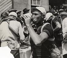 A man with a cap drinking from a bottle.