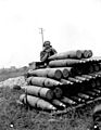 Canadian signaler with shells during a shoot, France July 1944.