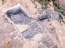 Satellite pic of very large rectangular pit with a dark base, and a much smaller power plant nearby