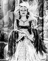 Dolores del Río usando un vestido que parece ser de piel, portando joyas, mirando fijamente a la cámara y con los brazos cruzados.