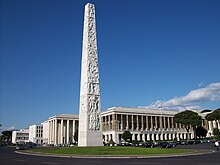 Photo d'un obélisque en marbre devant des grands bâtiments.