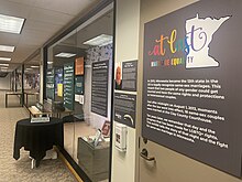 Looking down long built in wall exhibit case with exhibit panels and artifacts.