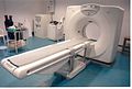 Typischer CT-Scanner: Im Bild vorne, rechts: Gantry und Patiententisch. links neben Gantry: die Kontrastmittelpumpe zur Verabreichung eines Kontrastmittels. In rechter Raumecke eine Stromversorgungseinheit mit Transformatoren, rechts daneben ein Geräteschrank.