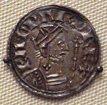 A coin depicting a bearded man facing to the right holding a sceptre, with a Latin inscription going from left to right over him