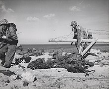 Marines crossing Japanese-laid barbed wire in Betio Island