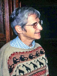 Gray-haired woman in sweater with African animal motifs standing in profile