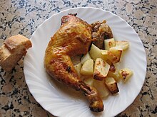 烤雞腿伴烤馬鈴薯，在白色餐盤上。