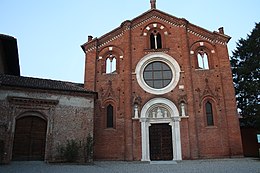 Façade en brique rouge ornée d'une grande ouverture circulaire centrale, de trois fenêtres à menau et d'un fronton, tous en pierre blanche, et munie d'un unique portail en bois.