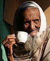 A man drinking tea in Bangladesh on a winter morning. Lines (wrinkles) can be seen on his face.