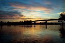 A black silhouette of a bridgr with a colourful sky