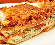 Close-up profile view of a lasagna casserole, showing the layers of sauce, cheese and other ingredients