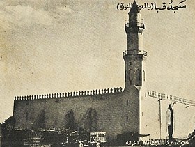 Vue en noir et blanc d'un monument quadrilatéral dont l'un des coins est surmonté d'un minaret