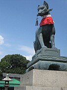 A fox in front of an Inari shrine with a key in its mouth