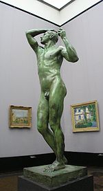 Life-sized nude stature of a male on a pedestal on display in a museum.