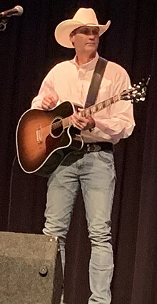 Singer Wade Hayes, holding a guitar while onstage.