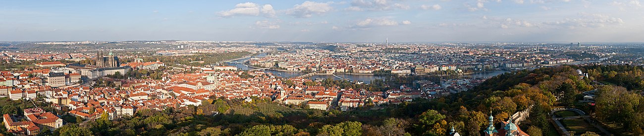 Panorama Prahy z Petřínské rozhledny. Vlevo jsou vidět Hradčany s Pražským hradem, jemuž dominuje svatovítská katedrála, pod nimi se rozkládá Malá Strana. Ve středu snímku pražský záhyb Vltavy obklopuje Staré Město. U horizontu leží Severní Město, Letná a Holešovice, Karlín, Vinohrady, Nové Město, Žižkov, Pankrác, Podolí i další čtvrti. V popředí snímku jsou zahrady vrchu Petřína, vpravo Růžový sad s věžemi starokatolického katedrálního kostela svatého Vavřince, Hladovou zdí, hvězdárnou a horní stanicí lanovky.