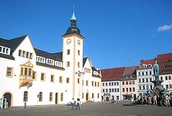 Barevná fotografie náměstí Obermarkt ve Freibergu s budovou radnice a hranolovou radniční věží s okolními domy